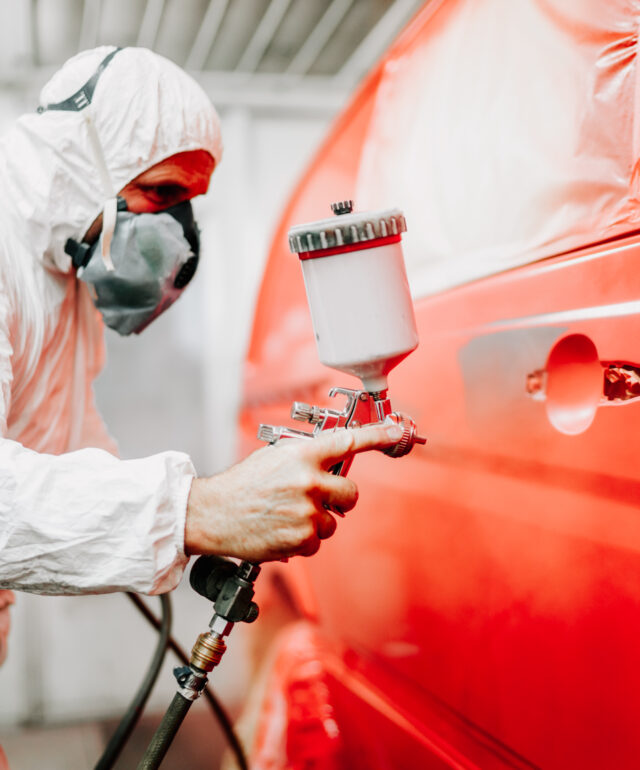 Close up details of mechanic worker, painting a red car